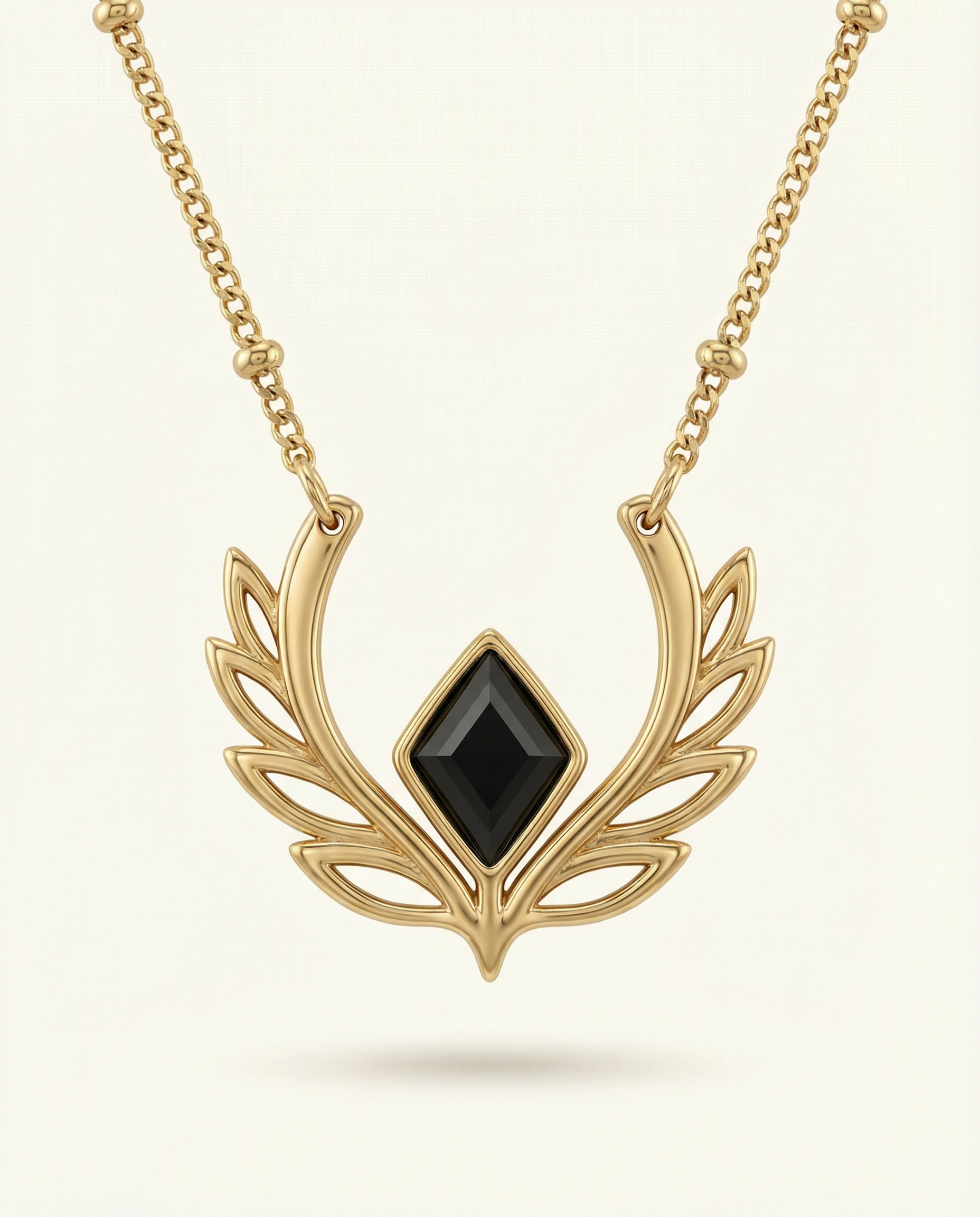 Gold necklace with a black gemstone on a light beige background