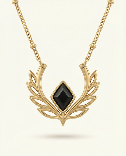 Gold necklace with a black gemstone on a light beige background