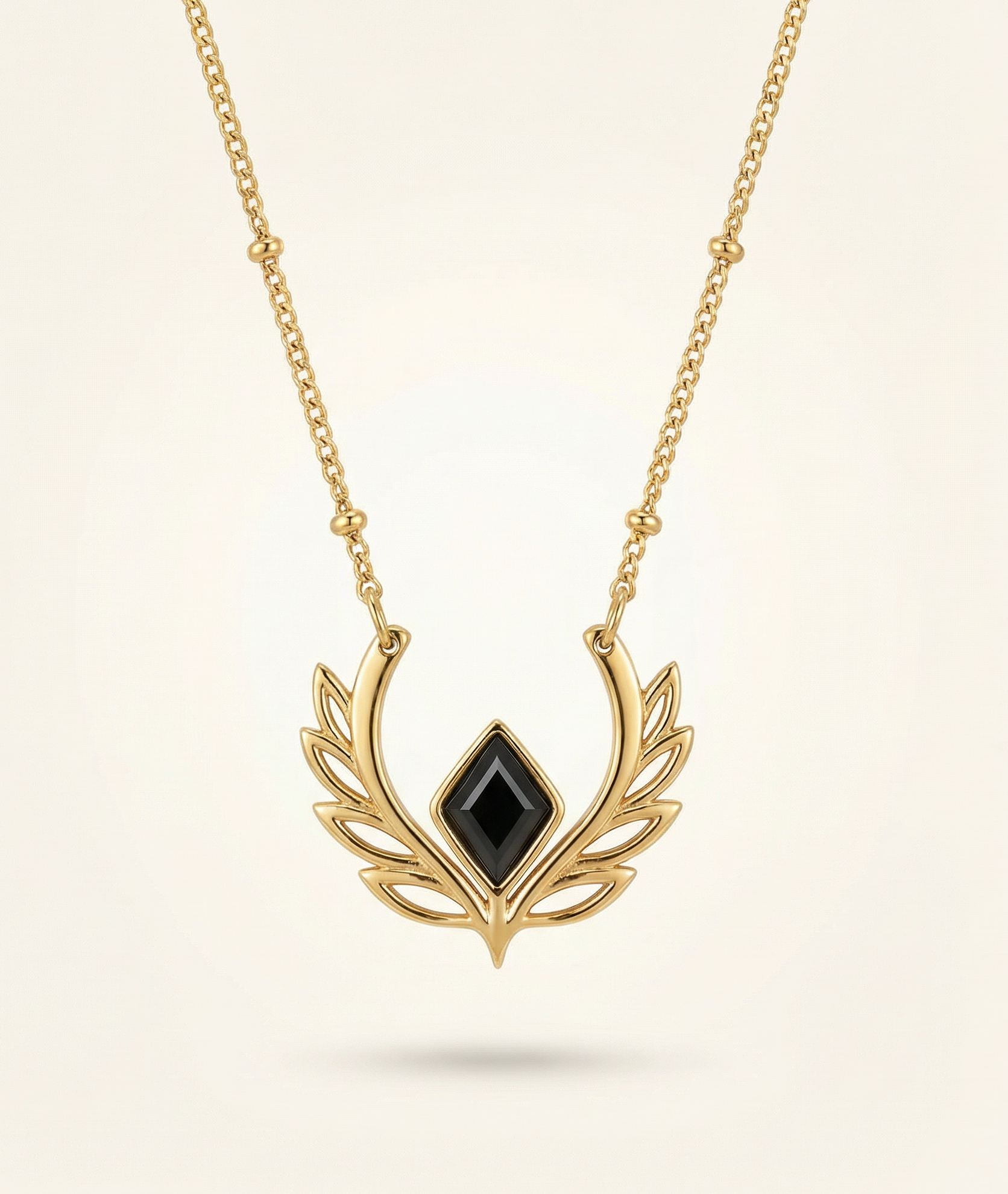 Gold necklace with a black gemstone pendant on a beige background