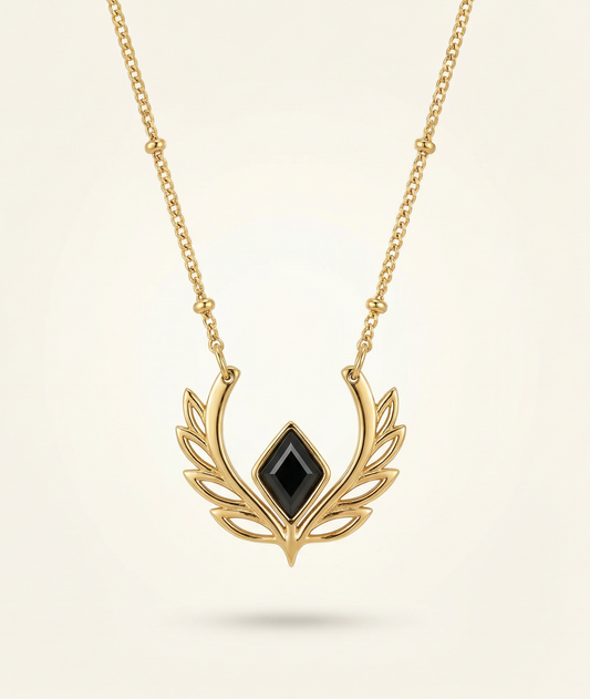 Gold necklace with a black gemstone pendant on a beige background