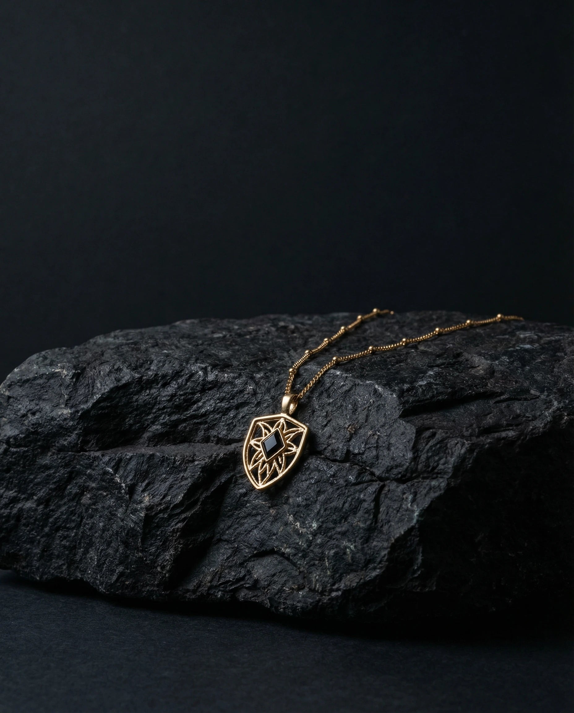 Gold necklace with a pendant on a dark stone surface