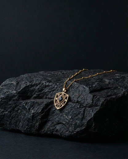 Gold necklace with a pendant on a dark stone surface
